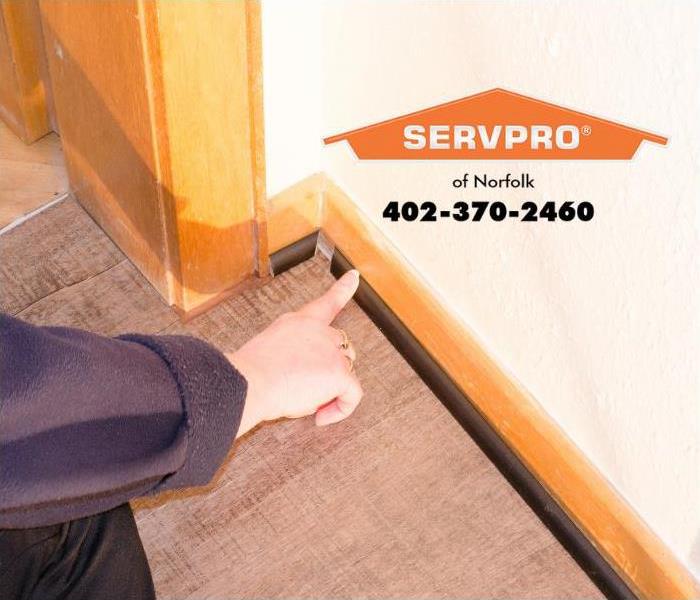 A person is inspecting a baseboard in a home.